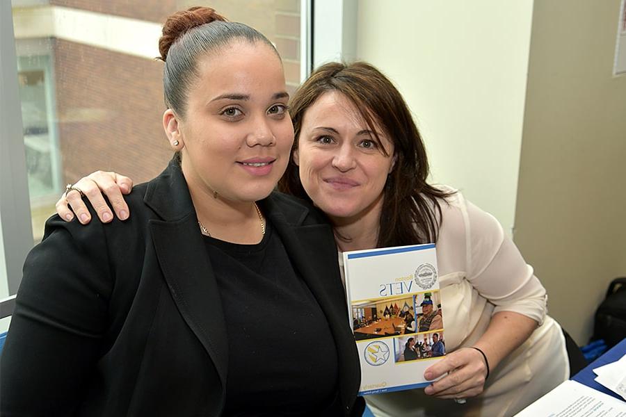 Two female veterans hold up a veterans brochure.